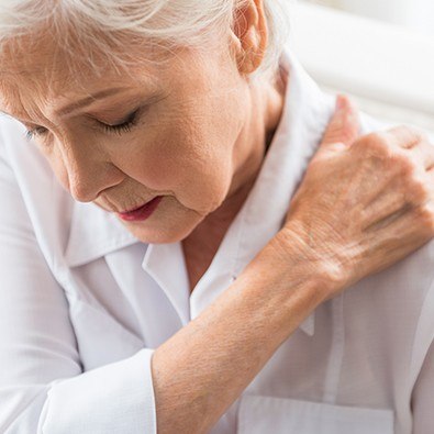 Older woman in pain holding her shoulder