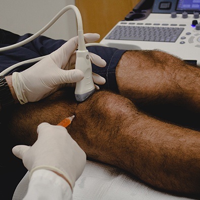 Doctor administering injecting in patient's knee