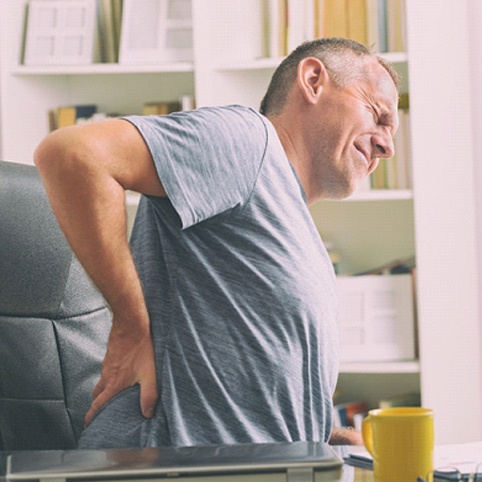 man sitting while experiencing back pain