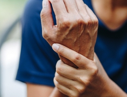 man in blue shirt holding wrist due to carpal tunnel syndrome 