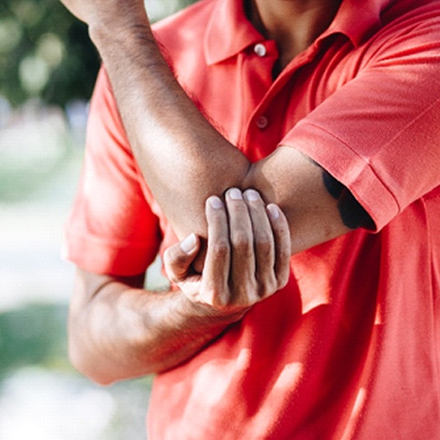 man holding elbow outside due to Tennis Elbow Symptoms