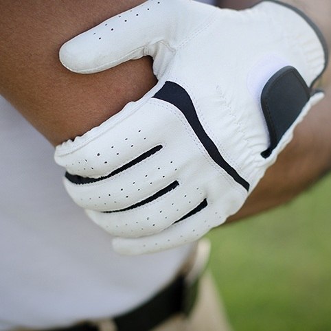 Hand in golfer's glove holding elbow