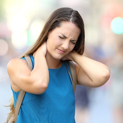 woman wearing backpack experiencing neck pain