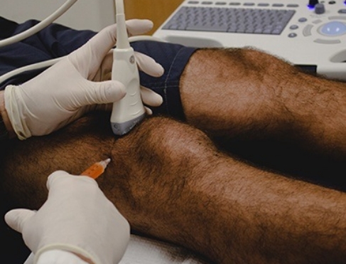 Doctor administering knee injection