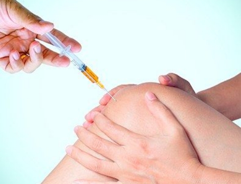 Doctor placing injection in knee