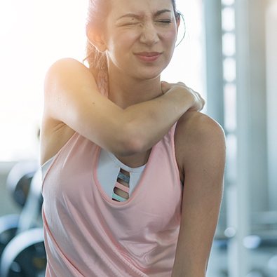 woman in gym holding shoulder in pain 