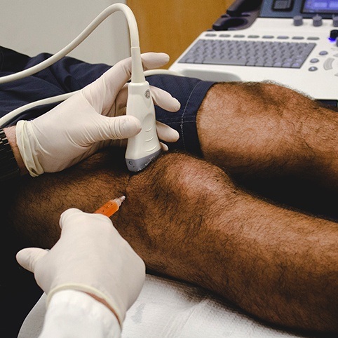 Doctor administering injection in knee