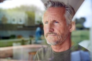 man looking out window worried about osteoarthritis
