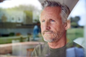 man looking out window worried about osteoarthritis 