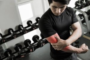 man holding arm due to muscle tear