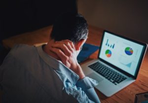 man holding neck while hunching over computer
