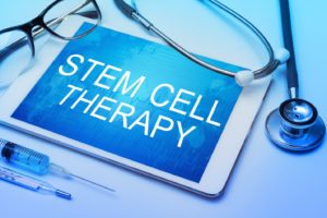 “Stem cell therapy” written on electronic tablet, surrounded by medical objects