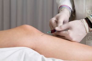 Doctor placing injection in patient’s knee