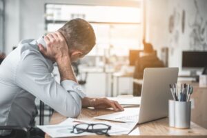 Man sitting at his desk, struggling with neck pain