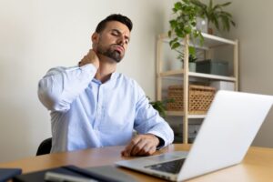 Man sitting at his computer, experiencing neck pain