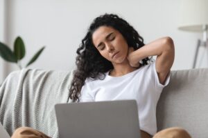 Woman struggling with neck pain while sitting at her computer
