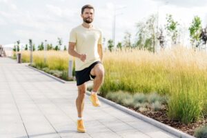 Man exercising outdoors, lifting his knee high 